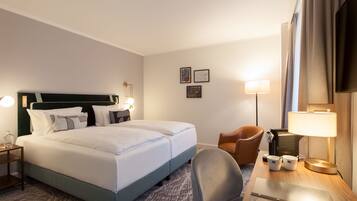 Una habitación de hotel con una cama grande, dos mesitas de noche con lámparas, un escritorio con una silla y un televisor.