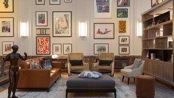 A modern living room with a sofa, armchairs, and a coffee table, surrounded by framed artworks on the walls.