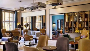 A spacious lobby with comfortable seating, a coffee table, and a bookshelf filled with decorative items. - Hotel Elephant Weimar, Autograph Collection (Weimar)