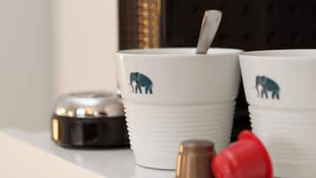 Eine Küchenarbeitsplatte mit einer Kaffeemaschine, zwei Tassen mit Elefantenmotiven, einem roten und einem braunen Behälter sowie einem Messingknauf.