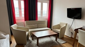 A modern living room with a sofa, two armchairs, a coffee table, and a TV mounted on the wall. - Sure Hotel by Best Western Muenchen Hauptbahnhof (Munich)