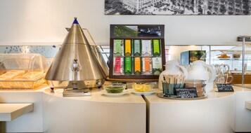 Eine Kaffeestation mit einer Kaffeemaschine, einer Auswahl an Kaffeekapseln und einem Schild, das auf heiße Milch hinweist.