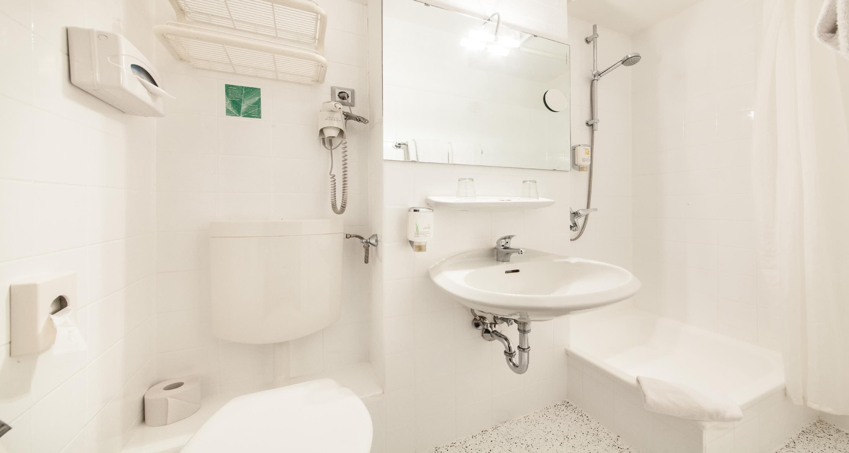 A modern bathroom with a toilet, bidet, sink, and shower.