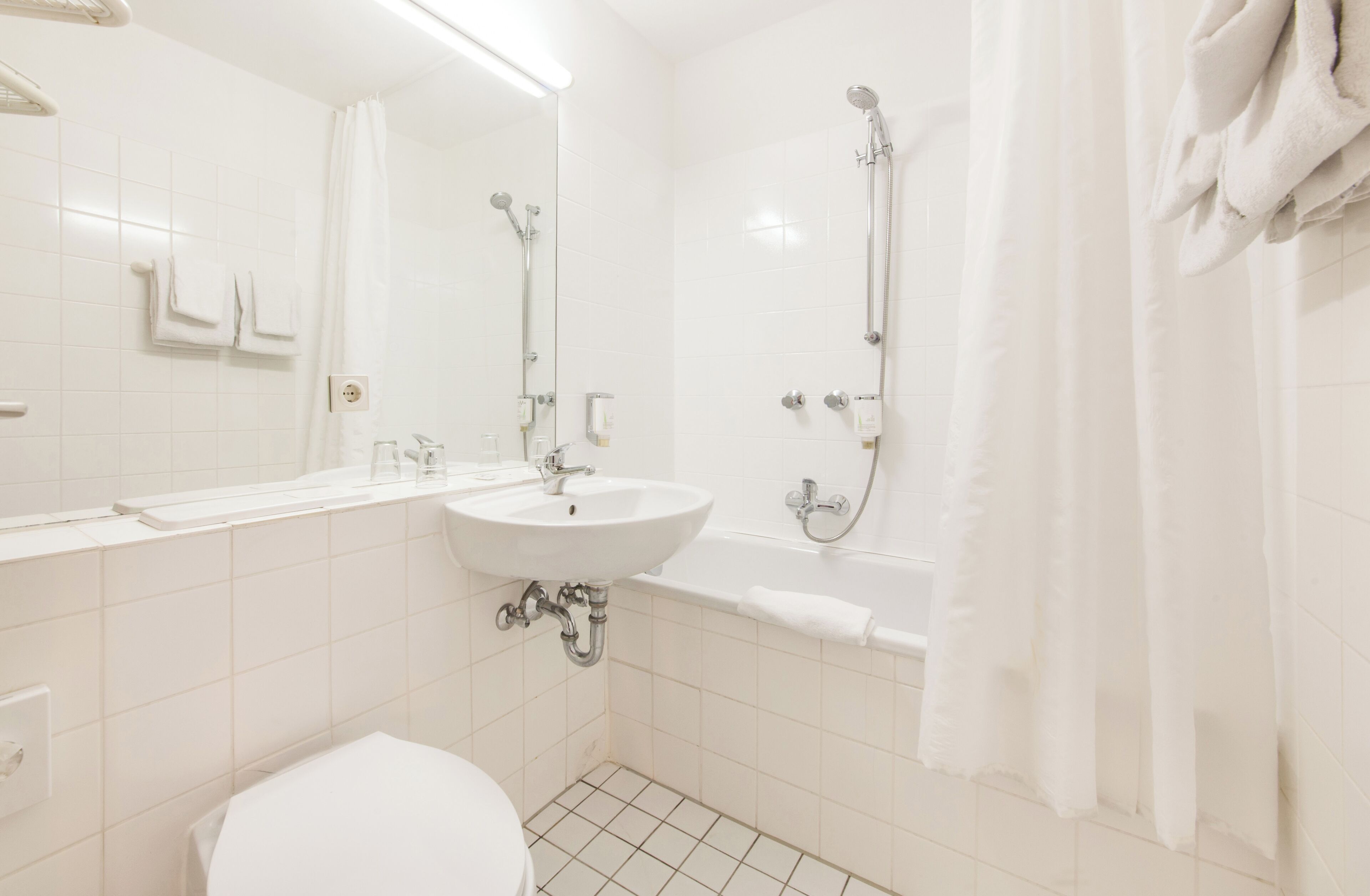 A bathroom with a sink, mirror, toilet, and shower.
