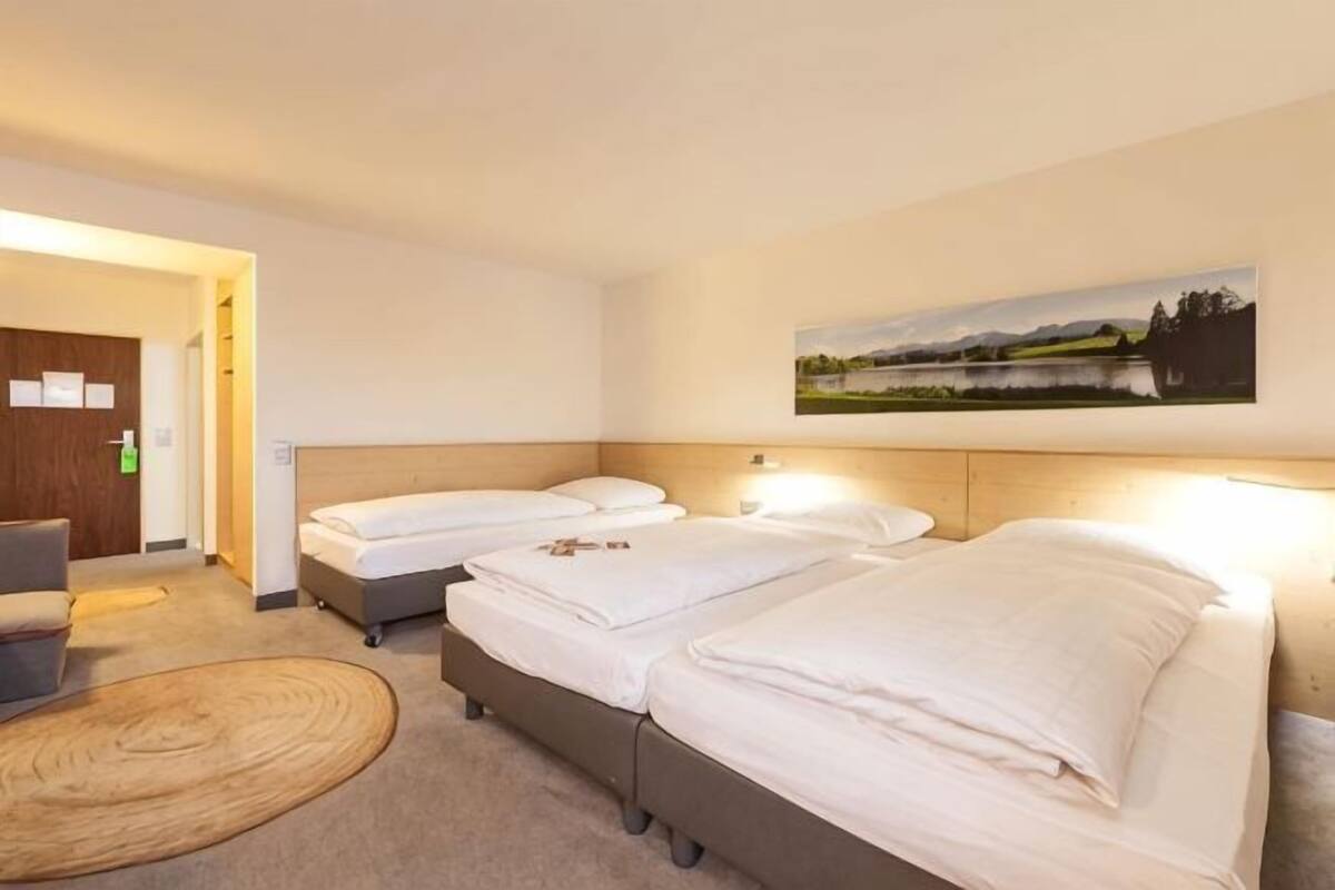 A hotel room with two beds, a desk, and a chair.