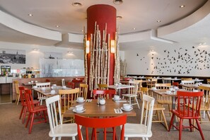 A modern dining area with multiple tables and chairs, a central decorative column, and a wall mural of birds. - Sure Hotel by Best Western Muenchen Hauptbahnhof (Munich)