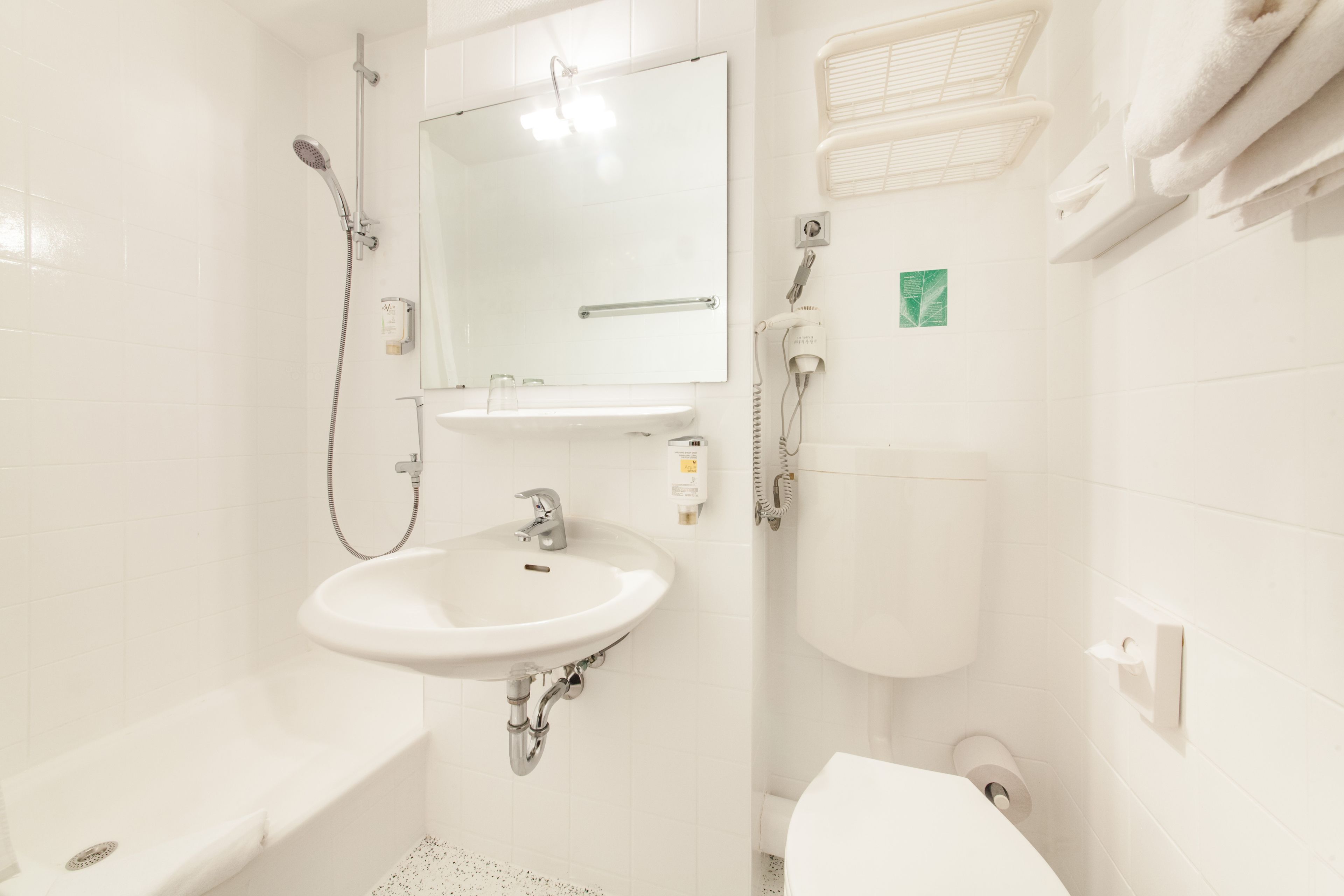 A bathroom with a sink, mirror, shower, toilet, and towel rack.