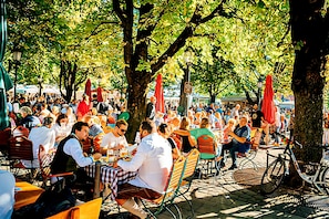 An outdoor café with tables and chairs, surrounded by trees and umbrellas. - Sure Hotel by Best Western Muenchen Hauptbahnhof (Munich)