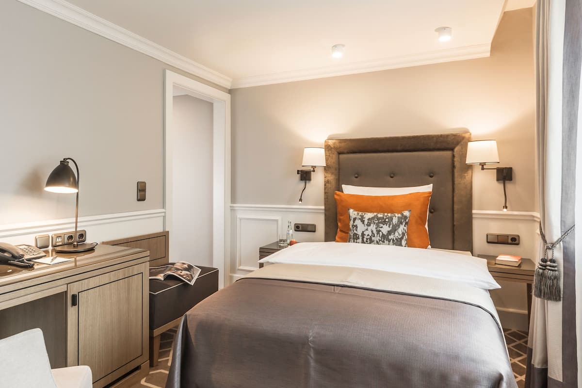 Een hotelkamer met een bed, nachtkastjes, een bureau, een telefoon en een lamp.