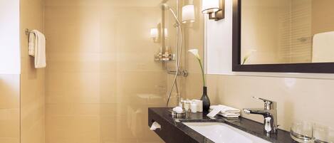 A modern bathroom with a glass shower enclosure, a black marble sink, and a large mirror.