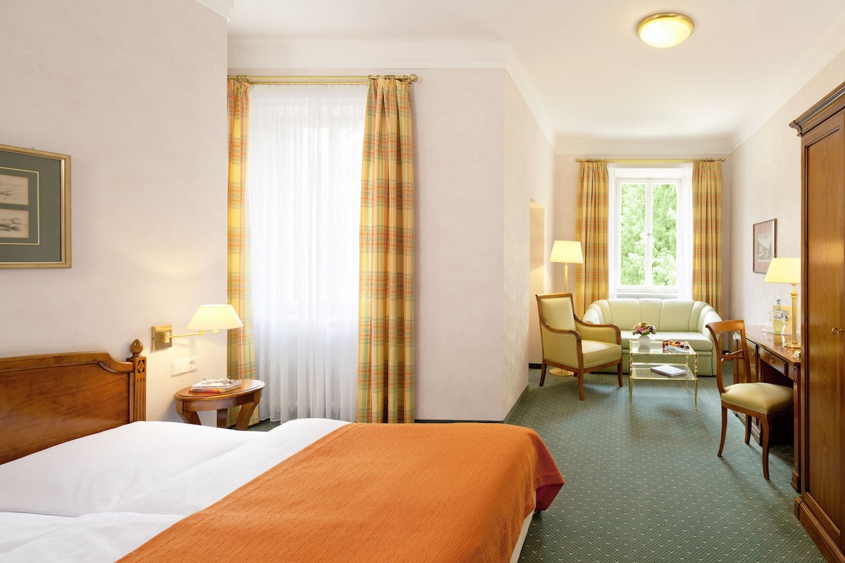 A hotel room with a bed, a sofa, a desk, and a chair.