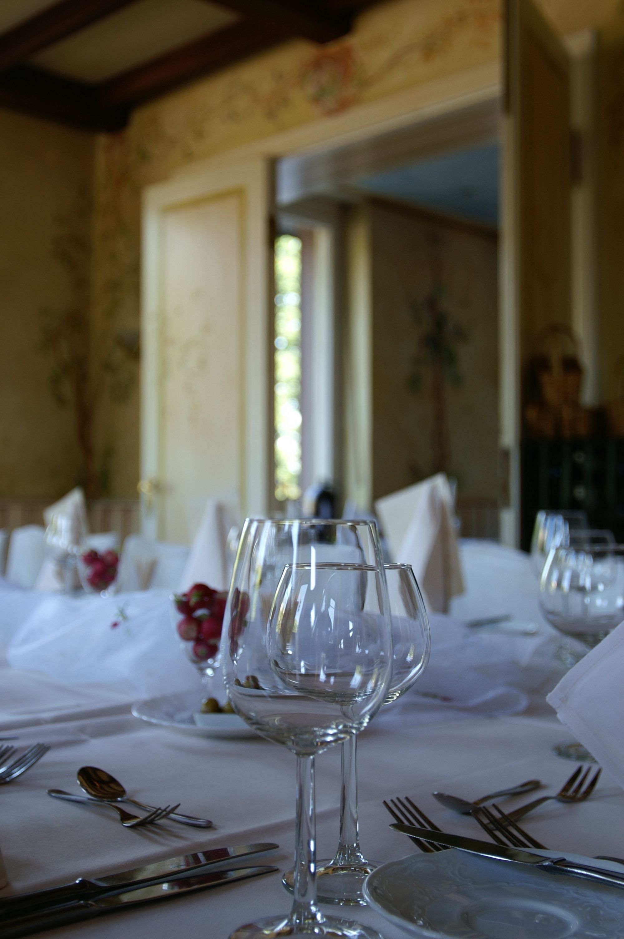 A dining table set with wine glasses, plates, and cutlery.