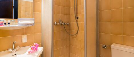 A bathroom with a glass-enclosed shower, a sink with a mirror, and a toilet.