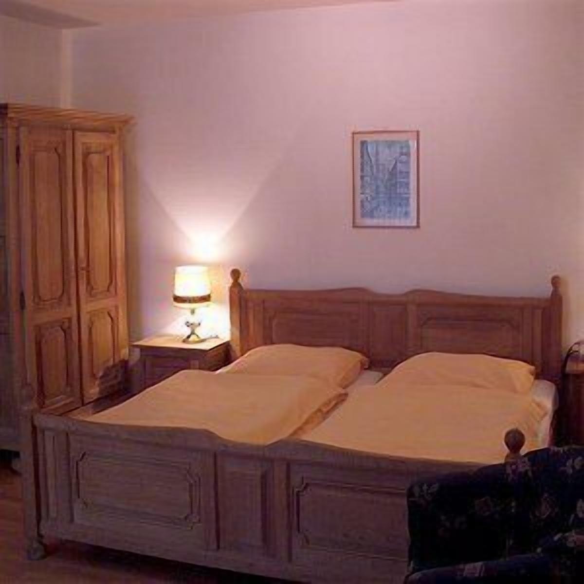 Un dormitorio con una cama de madera, una mesita de noche con una lámpara y un armario.