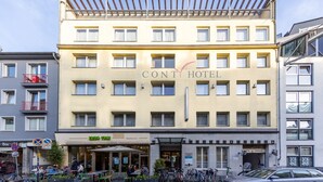 Ett hotell med flera våningar, en gul fasad, en uteservering och ett synligt garage.