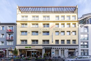 Un hotel de varios pisos con fachada amarilla, zona de estar al aire libre y un garaje visible.