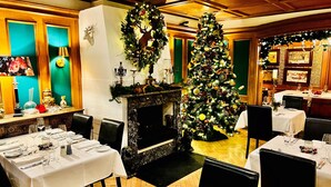 A restaurant with tables set for dining, a Christmas tree, and a fireplace. - Hotel Ashley's Garden (Düsseldorf)