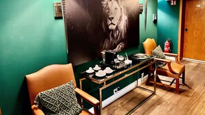 A modern room with teal walls, a large lion painting, a dining table with chairs, and a fire extinguisher. - Hotel Ashley's Garden (Düsseldorf)