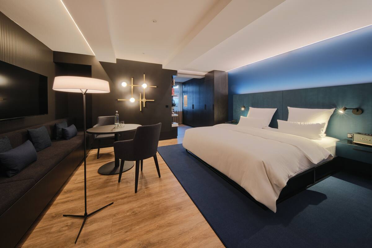 Une chambre d’hôtel moderne équipée d’un grand lit, d’un bureau avec une chaise, d’un canapé et d’une t élévision.