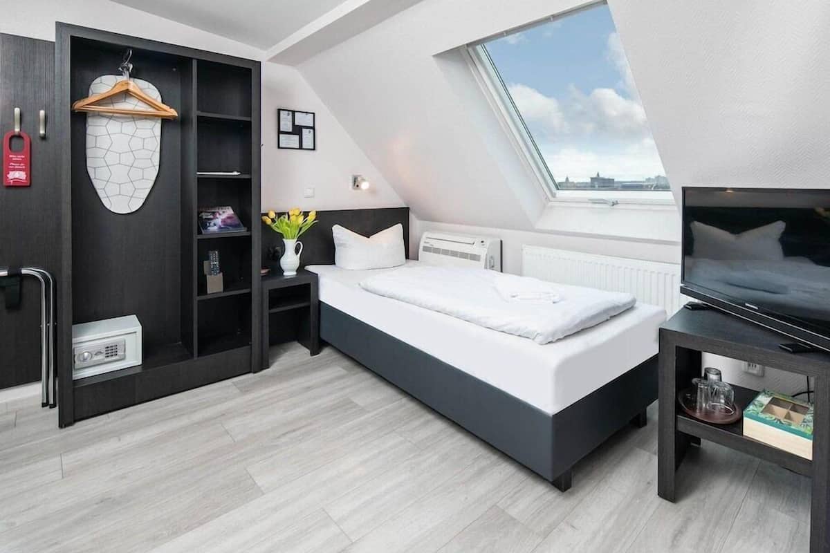 Ein modernes Schlafzimmer mit Dachfenster, einem Bett, einem Fernseher und einem Kleiderschrank.