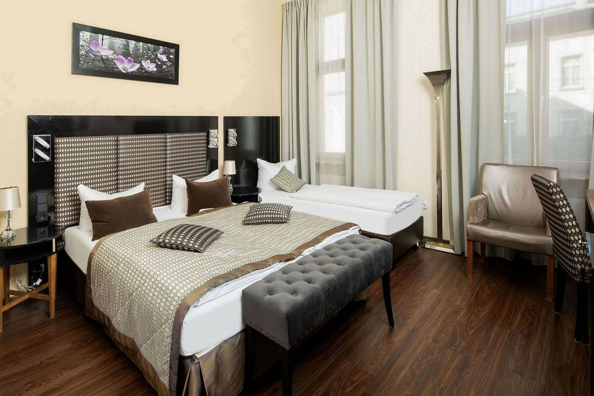 Ein Hotelzimmer mit Bett, Sessel, Schreibtisch und Lampe.