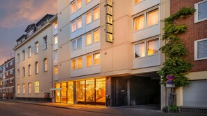 Ein Hotel mit einem großen 'HOTEL'-Schild, einem Glastür-Eingang und einem Parkschild, das eine Parkdauer von 15 Minuten anzeigt.