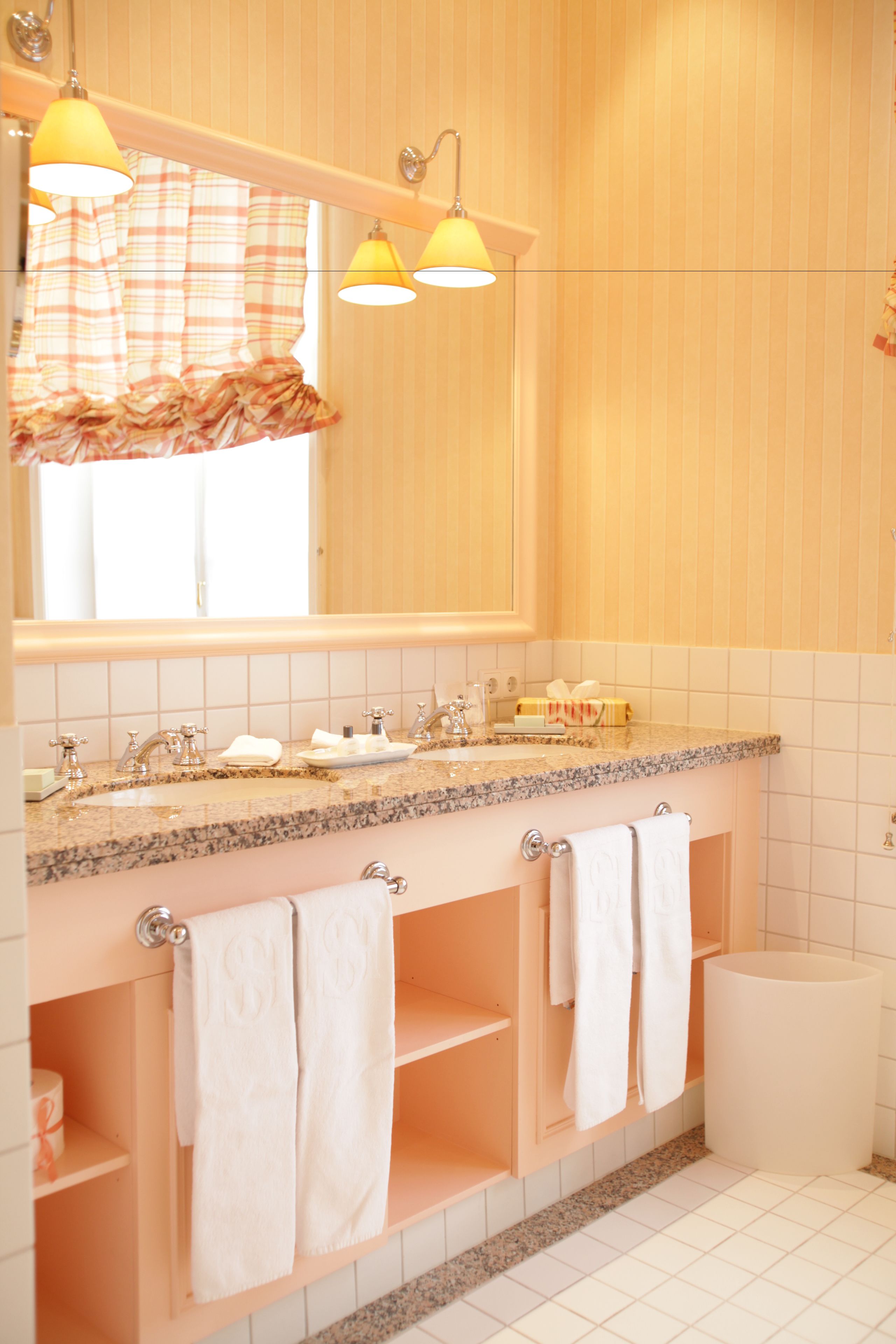 Un baño con tocador, lavabo, espejo y perchero para toallas.