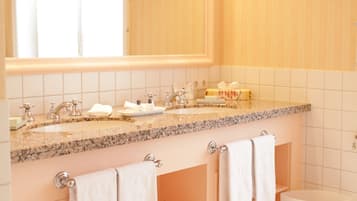 Un baño con tocador, lavabo, espejo y perchero para toallas.