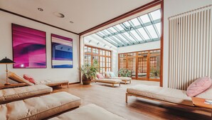 A spacious living area with multiple seating options, large windows, and artwork on the walls. - Hotel Stadt Hamburg (Sylt)