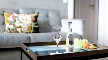 A glass of water, a bottle of Magnus, and a fruit platter on a tray.
