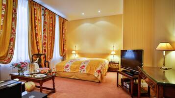 Een hotelkamer met een bed, een televisie, een bureau met een lamp en een stoel.