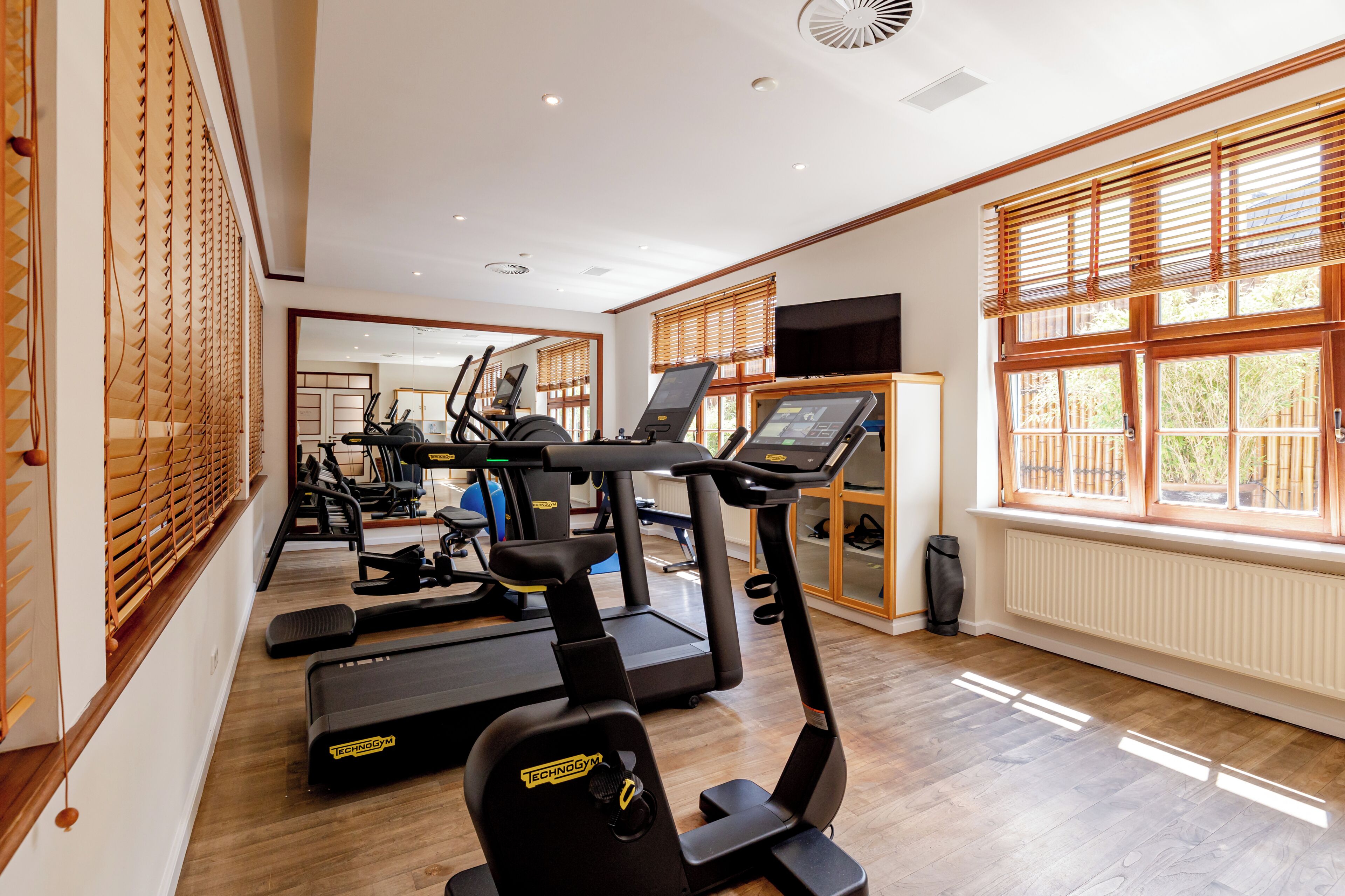 A gym with exercise equipment, large windows, and a view of the outdoors.