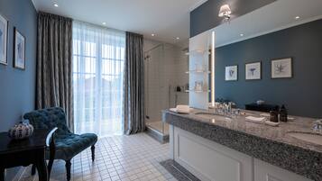 Une salle de bain moderne dotée d’un grand miroir, d’un plan de travail en granit et d’un espace douche.