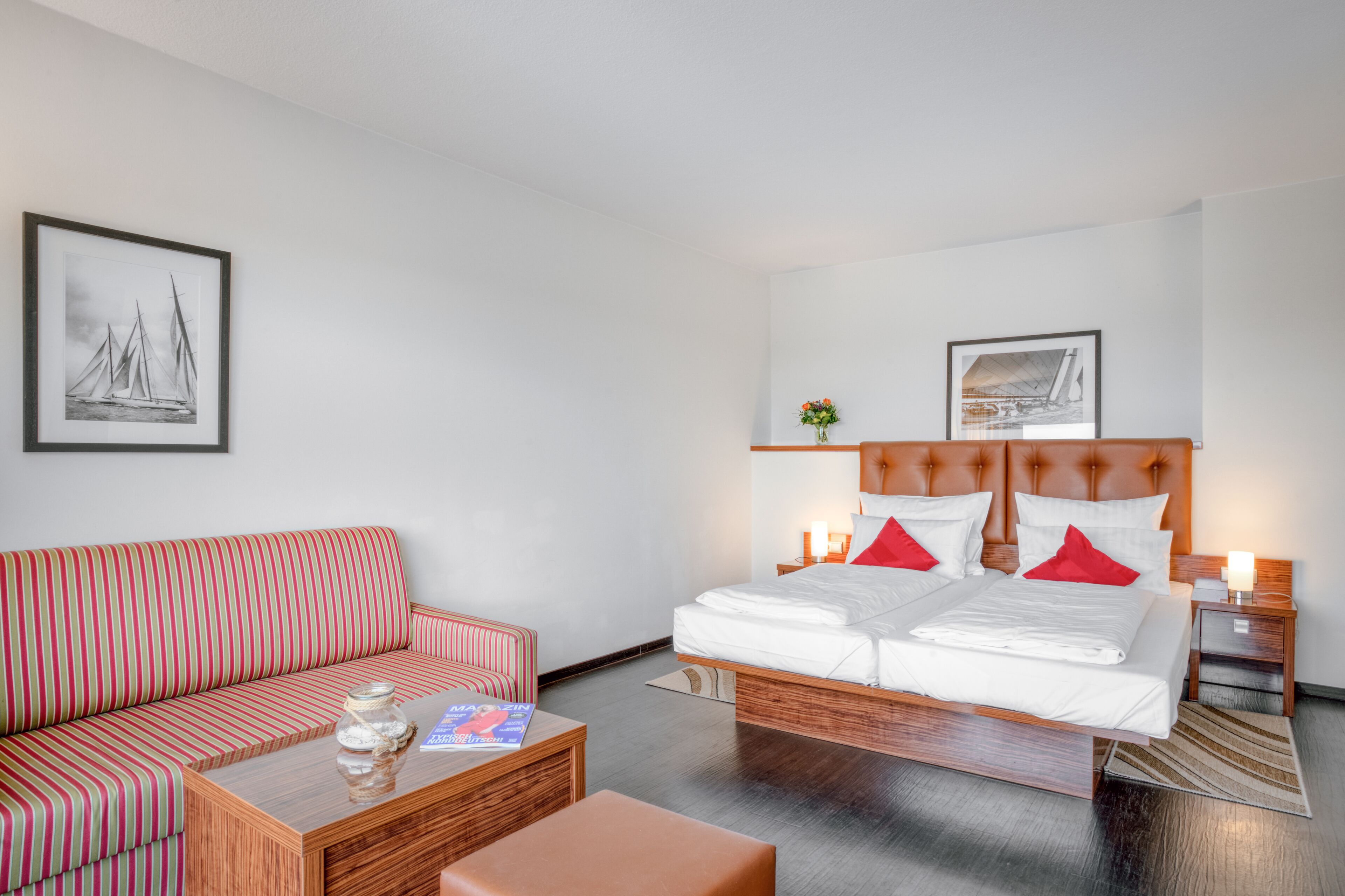 Une chambre d’hôtel avec un lit, un canapé, une table basse et deux tableaux accrochés au mur.