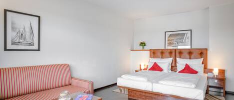 Une chambre d’hôtel avec un lit, un canapé, une table basse et deux tableaux accrochés au mur.