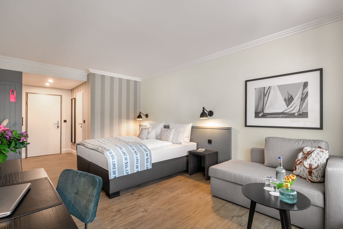 Une chambre d’hôtel moderne équipée d’un lit, d’un canapé, d’une petite table et d’un bureau avec un ordinateur portable.