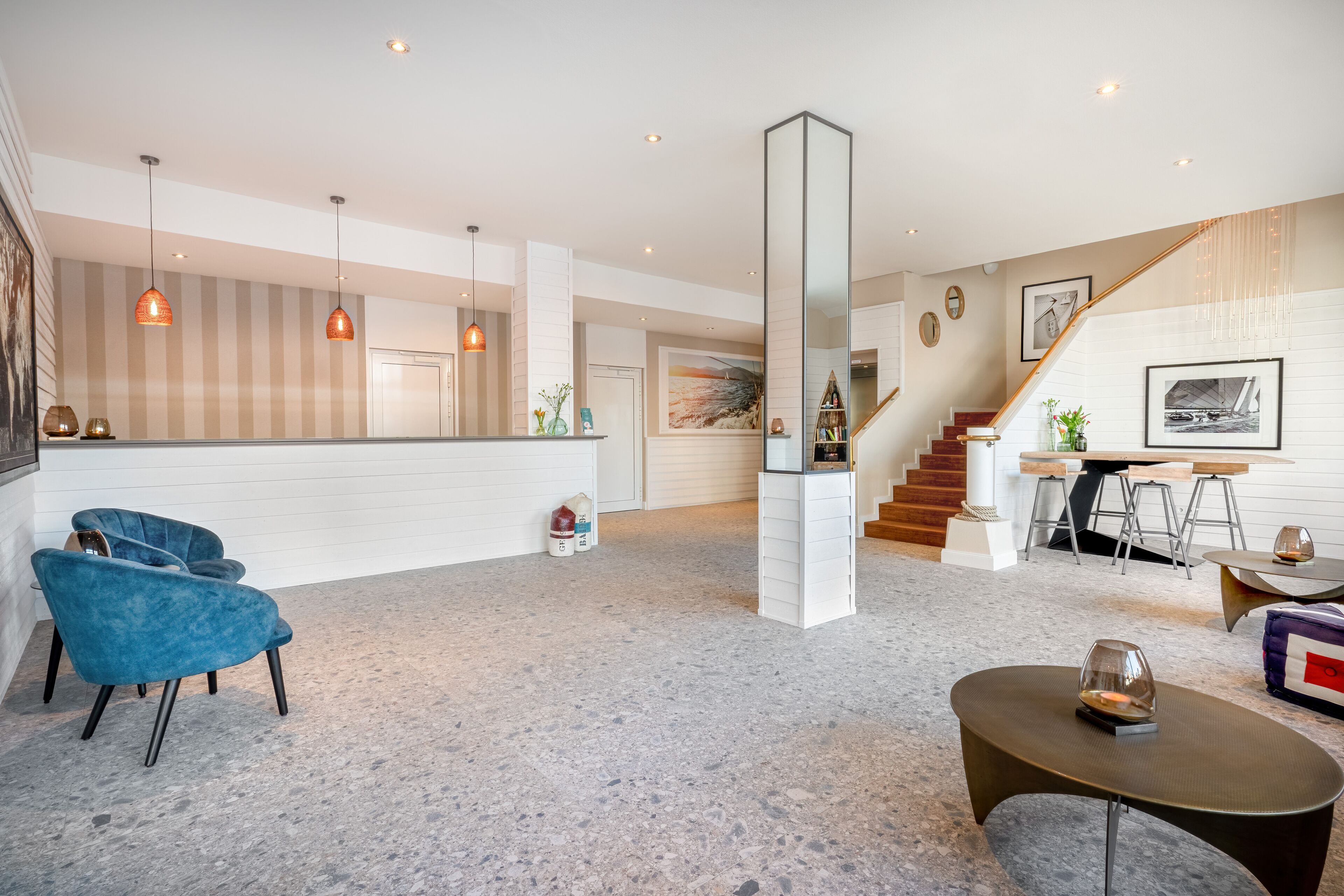 A spacious living area with a high ceiling, a staircase, and a kitchen area.