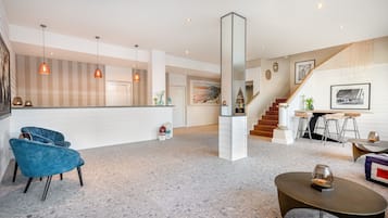 A spacious living area with a high ceiling, a staircase, and a kitchen area.