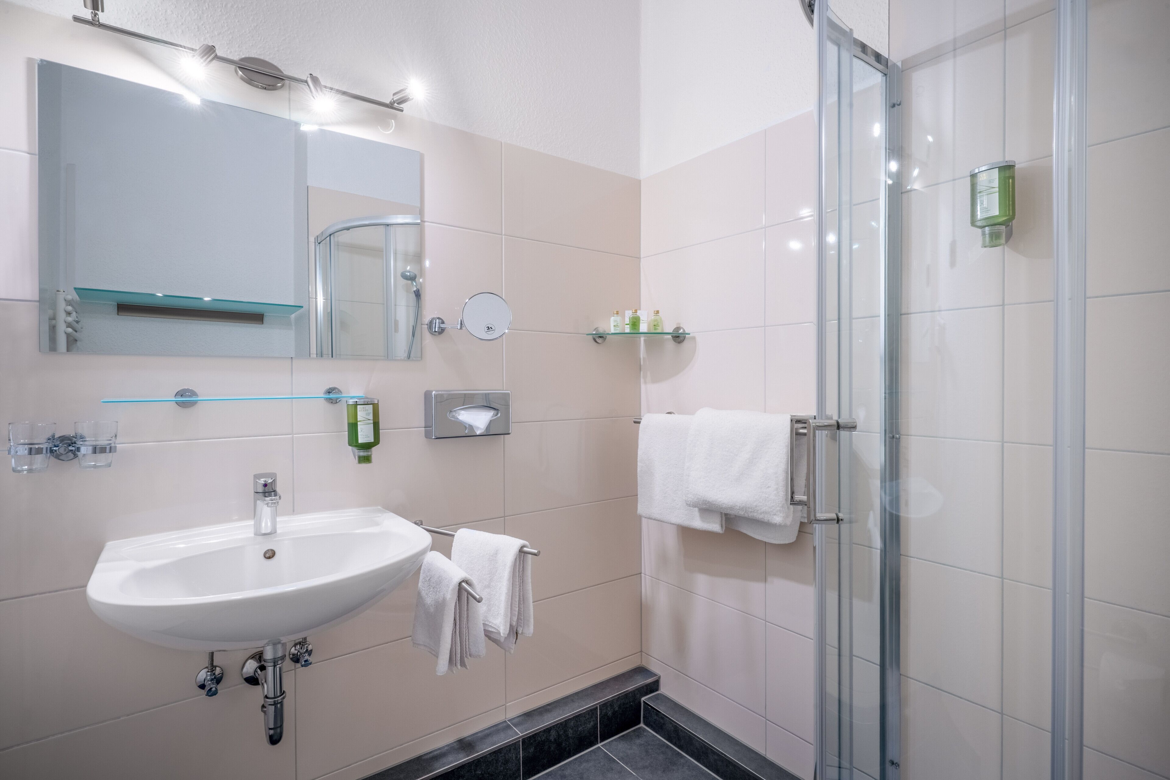 Un bagno moderno con lavandino bianco, specchio e cabina doccia in vetro.