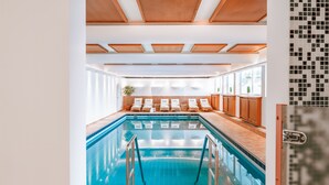 Ein Pool mit Fliesen umrandet, einer Holzbalkendecke und einer Reihe von Liegestühlen.