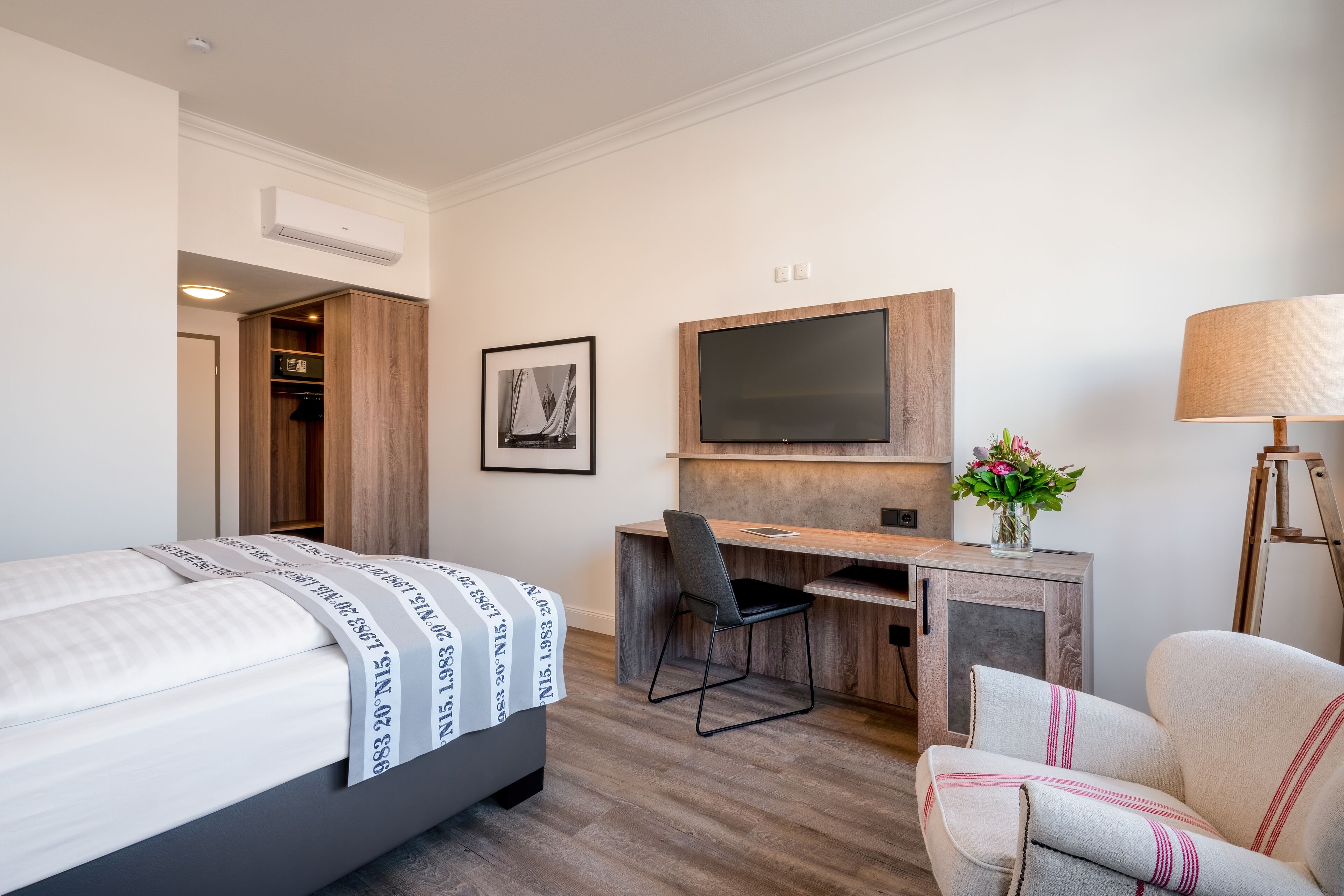 Une chambre d’hôtel avec un lit, un bureau, une chaise, une télévision et une lampe.
