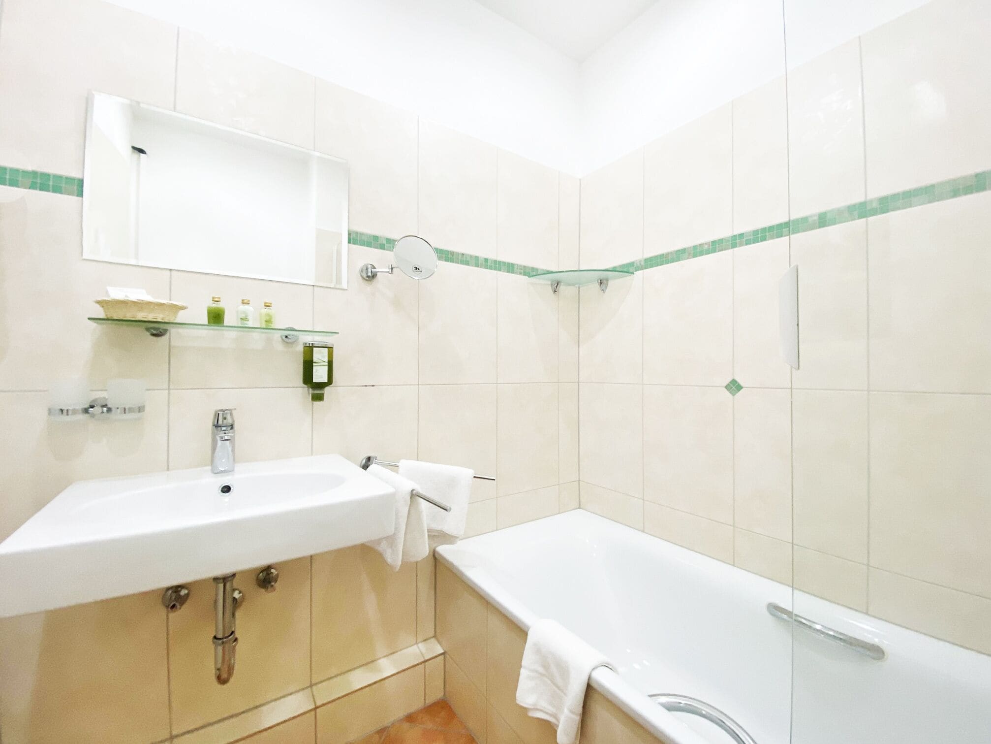 A bathroom with a sink, mirror, and bathtub.