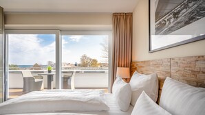 Ein Hotelzimmer mit einem großen Bett, einem Balkon mit Tisch und Stühlen und Blick auf die Stadt.