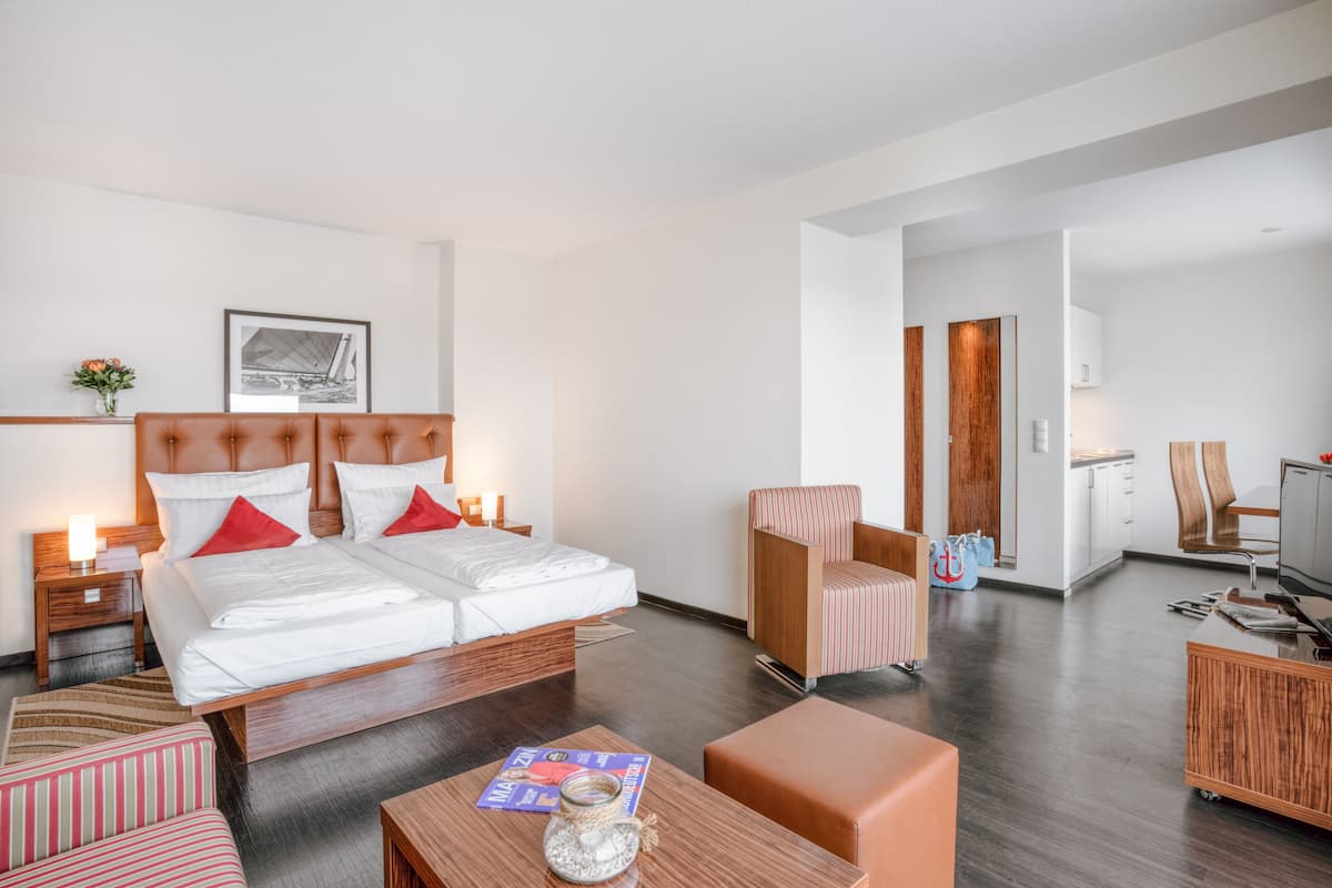 Une chambre d’hôtel moderne dotée d’un grand lit, d’un coin salon avec une table basse et d’une kitchenette.