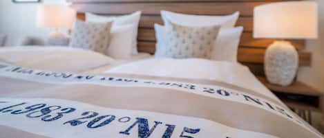 Una cama bien hecha con cabecera, almohadas y una manta con texto.