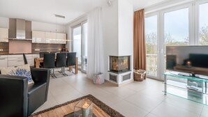 Ein modernes Wohnzimmer mit Kamin, Glastisch und Flachbildfernseher.