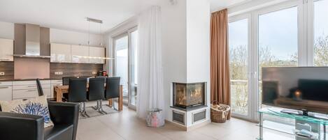 A modern living room with a fireplace, a glass coffee table, and a flat-screen TV.
