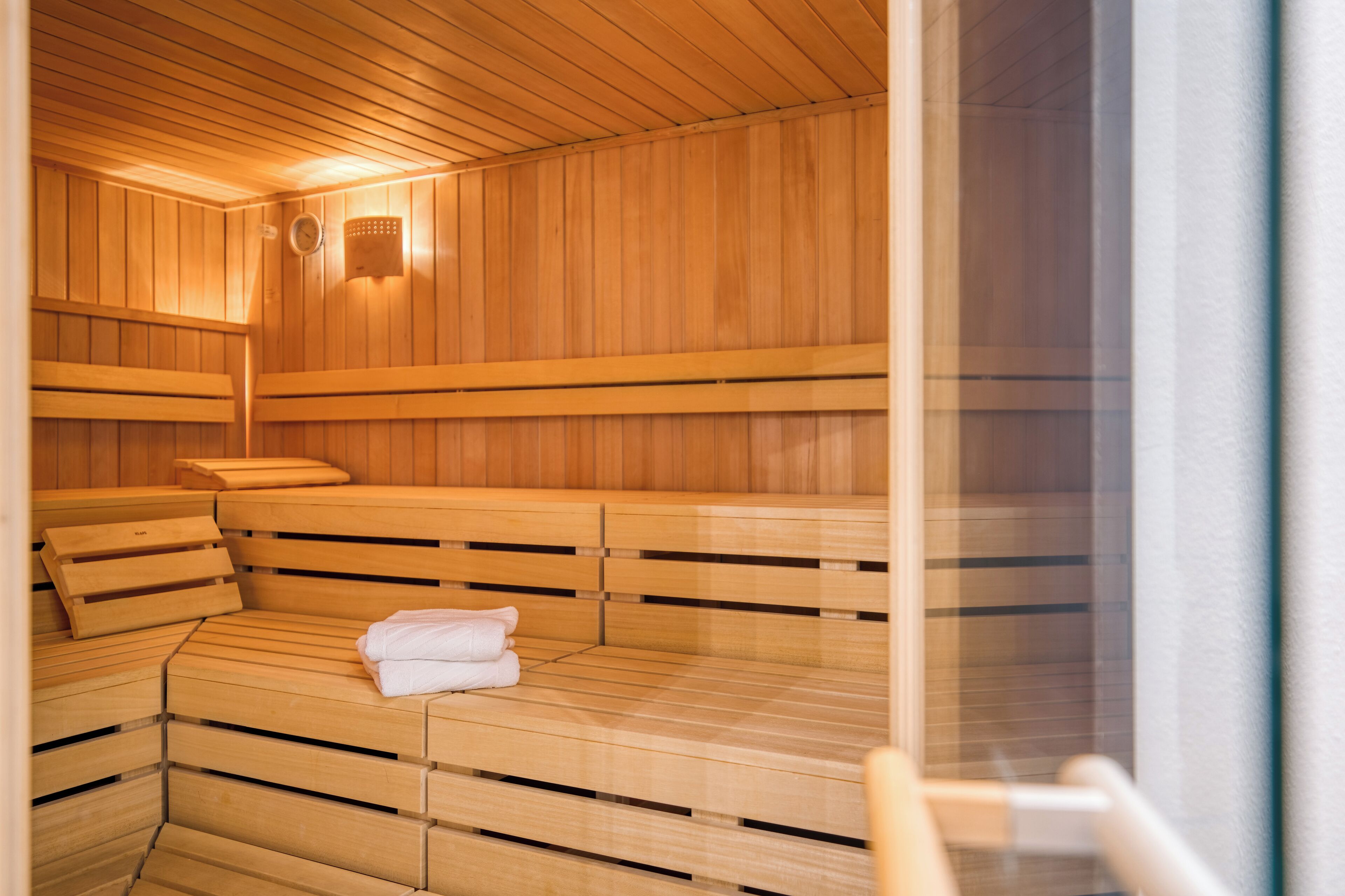 Una sauna con bancos de madera y un banco con toallas.