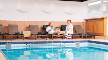 Una zona junto a la piscina con sillones de descanso, una piscina y un armario de madera.