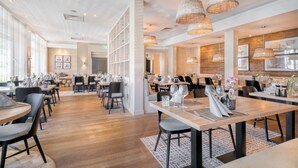 Ein geräumiges Restaurant mit mehreren Essplätzen, Stühlen und hängenden Korbstühlen.